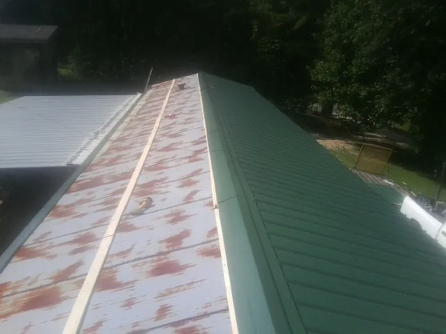 Old rusted panels beside newly installed green metal roofing — Wind Damage Roof Repair by Roofing Brothers in Shingletown