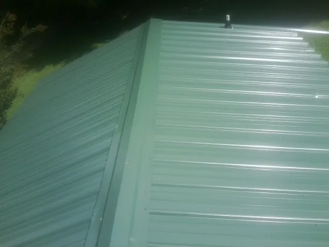 New green metal panels meeting at the ridge of a roof — Flat Roof Repair work by our crew in Shingletown