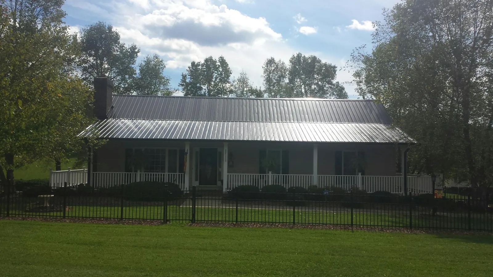 Gray metal roof on a brick ranch with a full width front porch — Gutter Guard Installation work by our crew in Shingletown