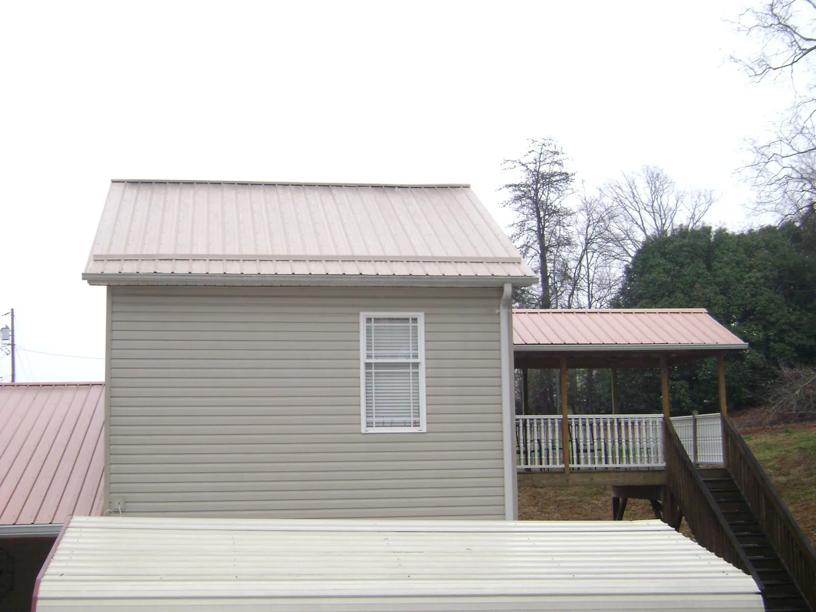 Tan metal roofs on a two story addition and attached porch, from a Roof Replacement job in Shingletown